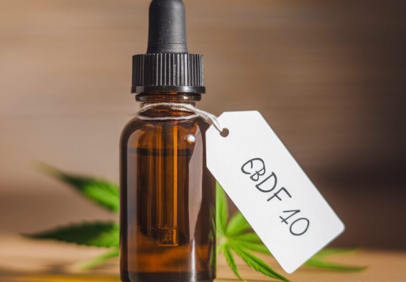 Flacon d'huile de CBD avec étiquette 'CBD pas cher' posé sur une table en bois